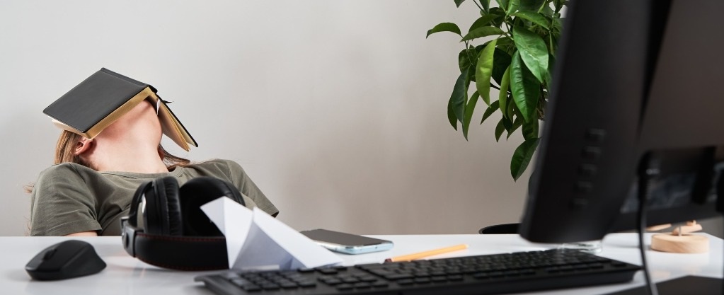 Quiet quitting: hoe het je carrière beïnvloedt! vrouw achter bureau met boek op jaar hoofd denkt aan ontslag