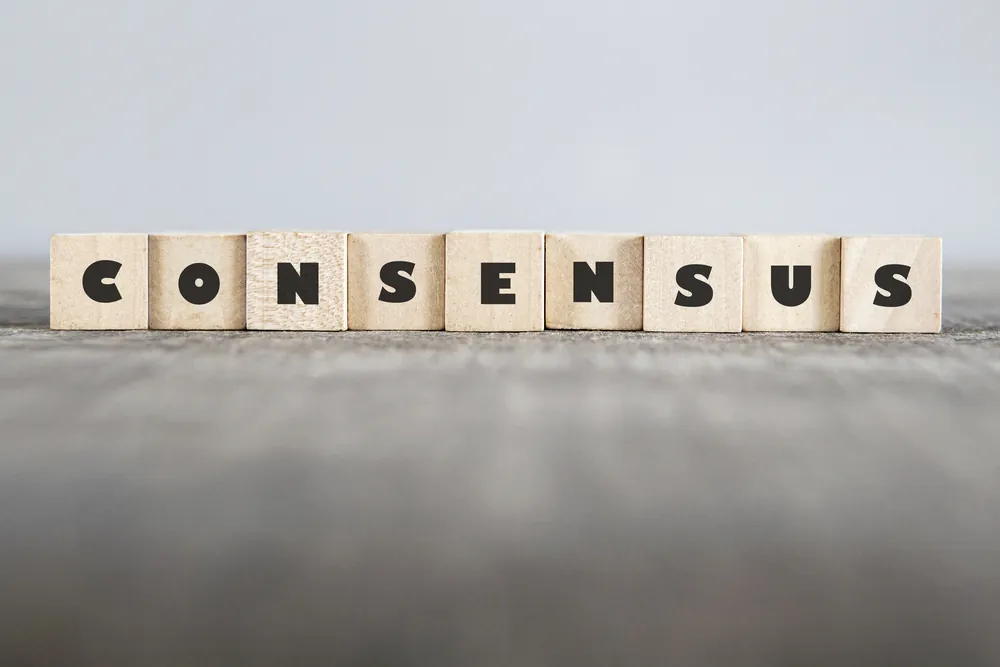 Houten blokjes met letters erop vormen het woord: consensus